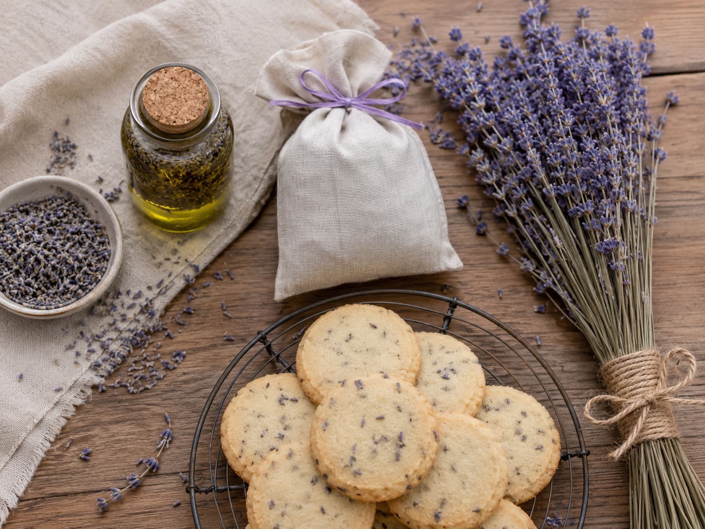 Illustration of lavender oil, a sleep sachet, shortbread cookies, and a hand-tied dried lavender bundle on wood.